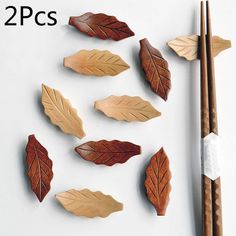 several wooden leaves and chopsticks on a white surface next to some chopsticks