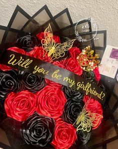 a black and red cake with roses on it that says will you be my girlfriend?