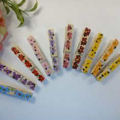 six different colored hair clips are arranged in a circle on a white surface next to flowers