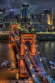 the city skyline is lit up at night, and it's lights shine brightly on the bridge