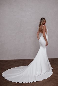 a woman in a white wedding dress standing on a wooden floor with her back to the camera