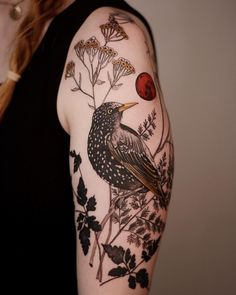 a woman with a bird and flowers tattoo on her arm