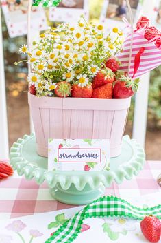 a basket filled with strawberries sitting on top of a table next to a sign