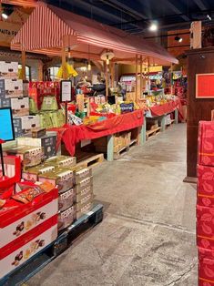 the inside of a grocery store with many items for sale on tables and red cloths