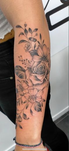 a woman's arm with flowers and leaves on it