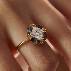 a woman's hand holding an engagement ring with blue and white stones on it