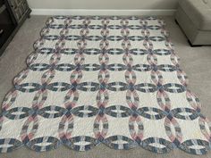 a large quilt is laying on the floor in front of a couch and table top