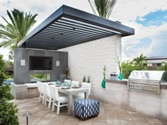 an outdoor tv sitting on top of a patio next to a table with chairs and a grill