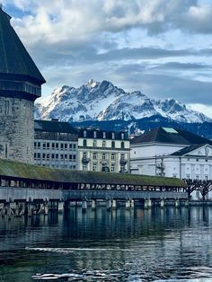 an old building is next to a body of water with mountains in the back ground