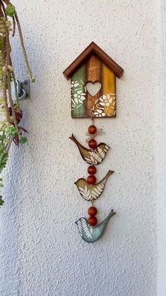 a bird house hanging on the side of a building with birds and flowers attached to it