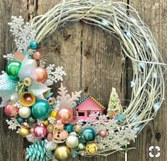 a wreath with ornaments hanging on a wooden fence