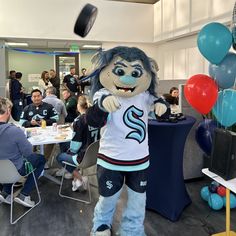 a mascot is standing in front of a table full of people