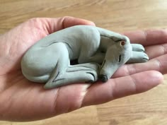 a hand holding a small clay animal sleeping