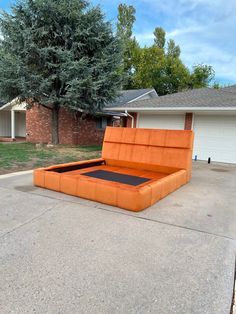 an orange couch sitting in the middle of a driveway