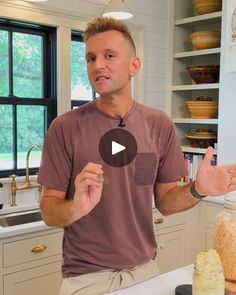 a man standing in front of a kitchen counter with jars on it and pointing to the camera