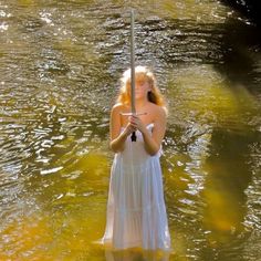 a woman standing in the water holding an umbrella