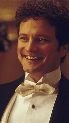 a man in a tuxedo smiles at the camera while wearing a bow tie