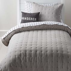 a bed with two pillows on top of it and a pillow that says wanderer