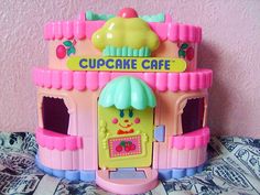 a pink and green cupcake cafe playset on a bed