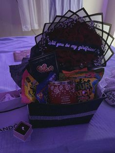 a gift basket is sitting on a bed with purple lights in the room behind it