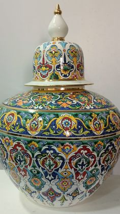 an ornately decorated jar with lid on a table