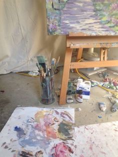 an artist's easel with paint and brushes in front of the easel