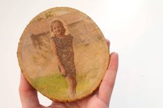 a hand holding a piece of wood with a photo on it