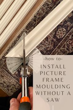 a person holding a pair of scissors with the words how to install picture frame moulding without a saw