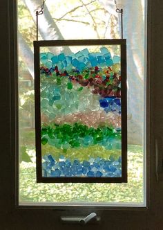 a stained glass window hanging on the side of a door in front of a tree