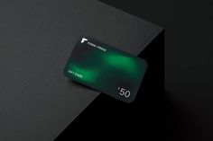 a green credit card sitting on top of a black surface