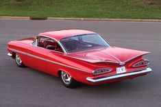 an old red car driving down the street