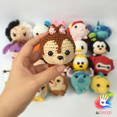 a hand is holding a small crocheted doll surrounded by other stuffed animals and toys