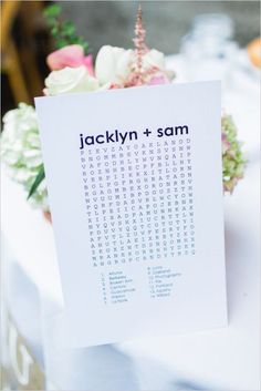 a white table topped with flowers and a card that says jacklyn + sam on it