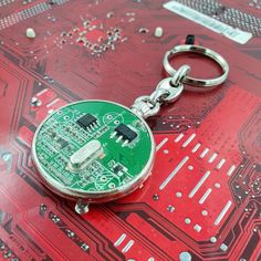 a green circuit board keychain sitting on top of a red surface