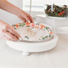 a woman is decorating a plate with flowers and the words happy birthday on it