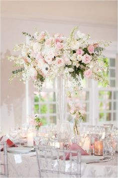 a tall vase filled with pink and white flowers on top of a dining room table