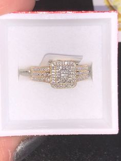 a person holding a ring in a white box with diamonds on it's sides