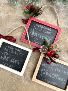 three chalkboard signs with christmas decorations on them sitting next to pine cones and twine