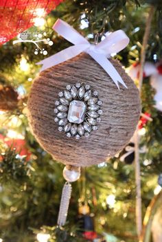 a christmas ornament hanging from a tree with a ribbon and bow on it