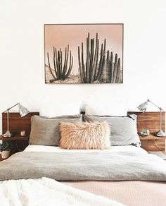 a bed with two pillows on top of it next to a painting above the headboard