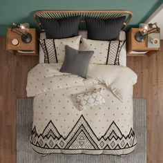 a bed with black and white pillows on top of it next to a night stand