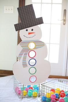 a snowman ball sorter sitting on top of a table next to colorful balls