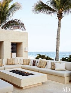 an outdoor seating area with palm trees and the ocean in the background