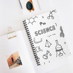 an open notebook with the word science written on it next to other items such as pens, scissors and eyeglasses