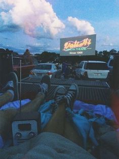 people are sitting in the back of a truck watching a movie on a large screen