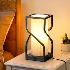 a lamp sitting on top of a night stand next to a nightstand with a potted plant