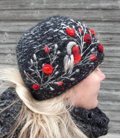 a woman wearing a knitted hat with red flowers on the front and back side