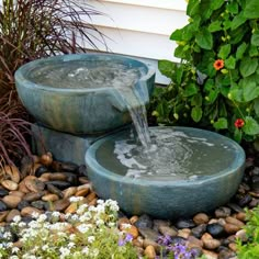 two water fountains sitting next to each other in a garden