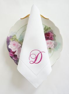 a napkin with the letter d on it sits next to a plate with a floral design