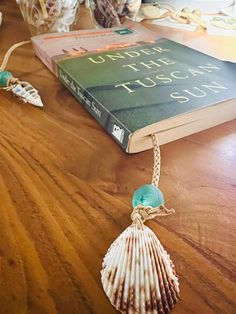 a book with a tassel on top of it sitting next to a seashell